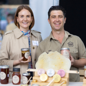 Holistic Hives founders holding honey jars with honeycomb display at event